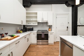 Fully equipped kitchen featuring stainless steel appliances, open counter space, and bar seating for 5 guests.