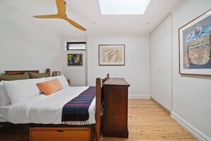 Sink into comfort in the skylit bedroom, warmed by soft light and cooled by a gentle ceiling fan—your private haven after a day out.