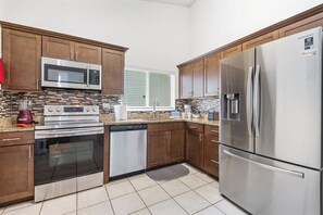 ully equipped kitchen featuring stainless steel appliances, granite countertops, modern tile backsplash, and all the essentials for preparing meals during your stay.