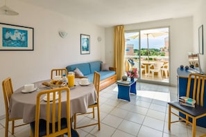 Enjoy a cozy meal in this inviting living and dining area, featuring a comfortable sofa and easy access to the balcony.