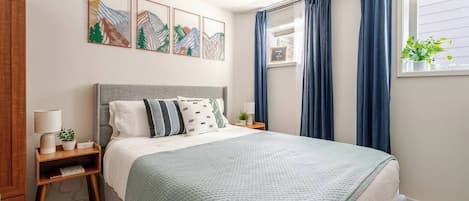 Comfy queen bed with room darkening curtains, soft lighting, cotton sheets.