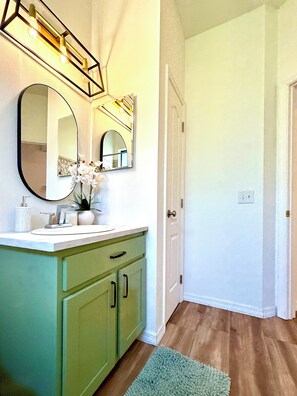 The bathroom features a tub-shower combination,vanity sink,toilet and hairdryer.