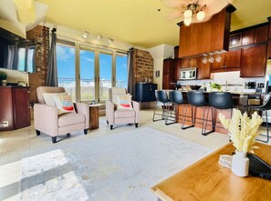 A spacious open-concept living area with plush chairs, a modern kitchen, and lake views—perfect for sipping coffee and sharing laughs with friends or family.