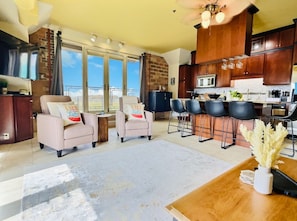 A spacious open-concept living area with plush chairs, a modern kitchen, and lake views—perfect for sipping coffee and sharing laughs with friends or family.