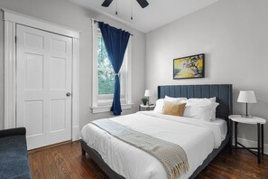 Enjoy a peaceful stay in our well-appointed queen bedroom, complete with a comfy mattress and soft, clean lines. A window provides natural light, and a bedside lamp offers convenient illumination.