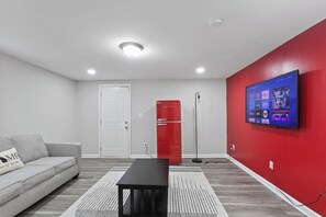 Your vibrant and cozy secondary living room, featuring a pop of boldness with a striking red accent wall and a retro red fridge. Unwind in this inviting space designed to add a touch of personality to your stay.