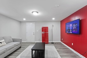 Your vibrant and cozy secondary living room, featuring a pop of boldness with a striking red accent wall and a retro red fridge. Unwind in this inviting space designed to add a touch of personality to your stay.