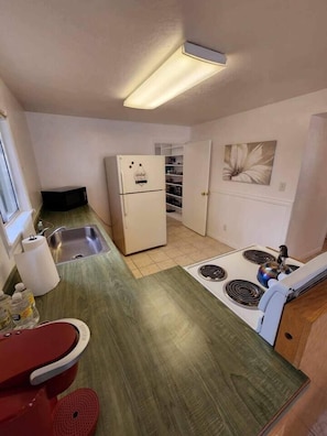 Kitchen of the 2 bedroom house with stove, oven, and fridge