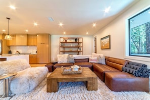 Living room has oversized comfortable furnishings including a leather sectional couch.