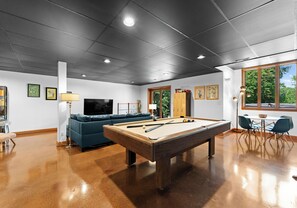 Game room with pool table, working space table, TV, and books, perfect for entertainment.
