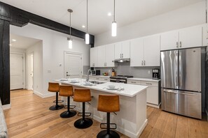 Fully equipped kitchen featuring stainless steel appliances, open counter space, and bar seating for 4 guests.