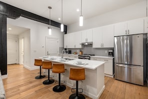 Fully equipped kitchen featuring stainless steel appliances, open counter space, and bar seating for 4 guests.