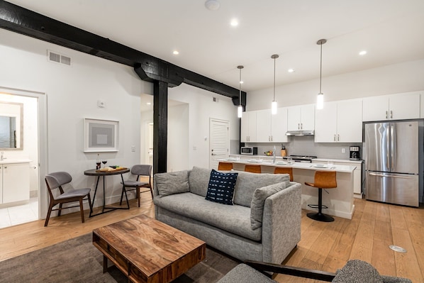 Open-concept living area featuring cozy furnishings, smart TV, small dining area with seating to 2 guests and a sleeper sofa.