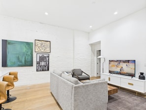 Open-concept living area featuring cozy furnishings, smart TV, small dining area with seating to 2 guests and a sleeper sofa.
