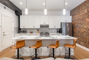 The kitchen features stainless steel appliances, a large island, and breakfast bar seating for four—ideal for casual dining.