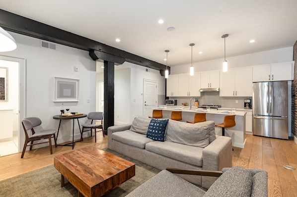 The living room features an open-concept design with a charming brick wall, cozy seating, and a Smart TV for relaxing nights in.