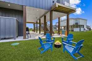 Cozy fire pit with bright blue chairs on a lush green yard — perfect for evening chats and s'mores