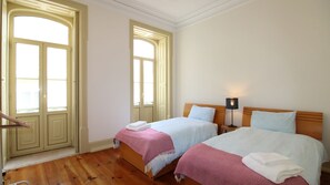 Ideal for friends or siblings, this twin-bed room is airy and inviting, with classic floor-to-ceiling windows and gentle natural light. #FamilyFriendly #Apartment #TwinRoom