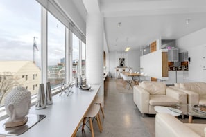 Step into a world of luxury and breathtaking views in our main living area, featuring plush sofas, a massive dining area, and panoramic views of the city and mountains.
