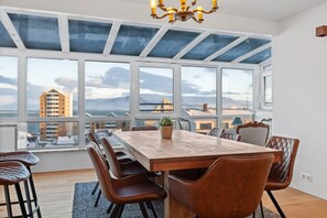 Dine under the ethereal glow of Reykjavík's sky in our spacious penthouse - where modern design meets comfort, surrounded by stunning cityscape views through panoramic windows