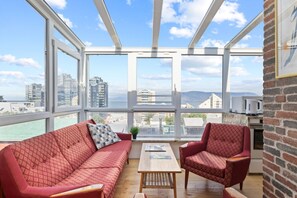 Unwind in style with breathtaking panoramic views of the city and the ocean from this cozy and inviting penthouse living room.