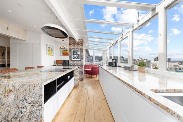 Immerse yourself in luxury with this stunning penthouse featuring a spacious kitchen and dining area bathed in natural light and offering breathtaking city views.