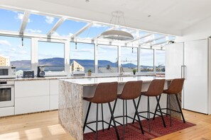 Enjoy breathtaking panoramic views of the city and mountains while cooking and dining in this modern, open-concept penthouse kitchen with a breakfast bar.