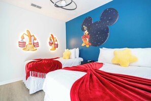 Cast a spell of comfort in this Sorcerer's Apprentice-themed bedroom! Enjoy a spacious queen bed plus cozy twin, star-shaped pillows, vibrant red throws, and whimsical broomstick art for a magical stay.
