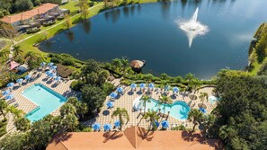 Soak up sunshine at our resort-style community deck overlooking a shimmering lake fountain, two sparkling pools, cozy loungers & shady blue umbrellas for endless relaxation!