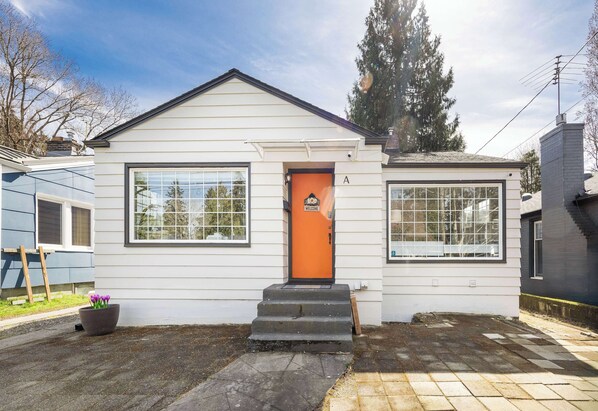 An orange door worthy of a Pantone swatch announces this cottage's welcoming spirit