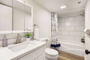 A combined tub-shower, crisp vanity, and mirror in a clutter-free space designed for ease.