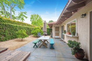 Enjoy the private backyard featuring dining space, ambient string lights, lounge chairs, BBQ grill