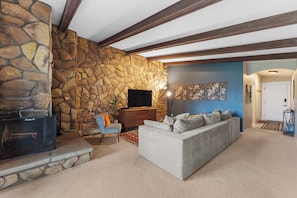 Living area featuring a queen sized sleeper sofa, smartTV, wood burning fireplace, and access to the private balcony.