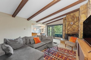 Living area featuring a queen sized sleeper sofa, smartTV, wood burning fireplace, and access to the private balcony.
