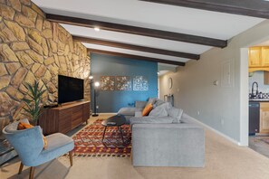 Living area featuring a queen sized sleeper sofa, smartTV, wood burning fireplace, and access to the private balcony.