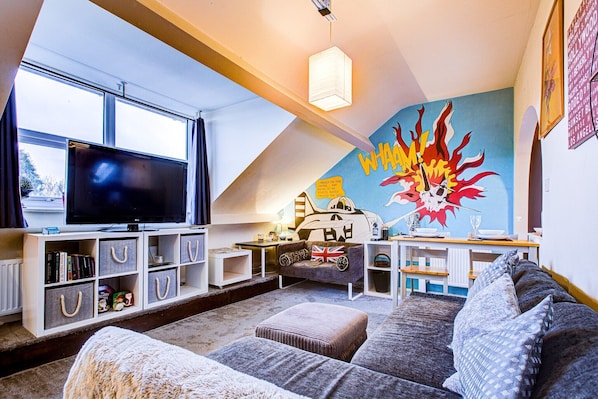 Living room with large TV, books and games