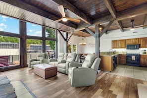 Spacious lower-level living room with big lakeview windows, seamlessly open to the kitchen and dining area—perfect for gathering, relaxing, and soaking in the view.