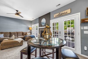 Lower-level living room with comfy seating, a pub table, wet bar, and direct deck access