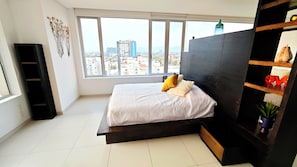 Indulge in the spacious master bedroom featuring a queen-size bed. Admire beautiful views through large windows and bask in the modern decor, creating a serene and stylish retreat.