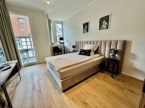 Helles Schlafzimmer mit Boxspringbett, Schreibtisch und Balkon – Blick auf die Altstadt inklusive.