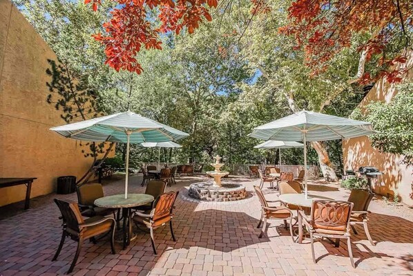 A charming outdoor area adorned with umbrellas and seating, ideal for enjoying shared BBQs surrounded by nature's tranquility.