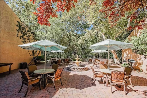 A charming outdoor area adorned with umbrellas and seating, ideal for enjoying shared BBQs surrounded by nature's tranquility.