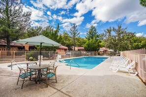 A bright and inviting outdoor pool area surrounded by lush greenery and lounge chairs, perfect for family fun and relaxation in the Sedona sun.
