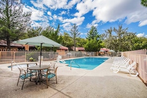 A bright and inviting outdoor pool area surrounded by lush greenery and lounge chairs, perfect for family fun and relaxation in the Sedona sun.