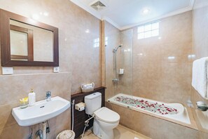 Ensuite bathroom with bathtub and rain shower at Villa Griya Purnama