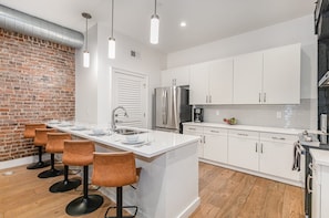 Fully equipped kitchen featuring stainless steel appliances, open counter space, and bar seating for 5 guests.
