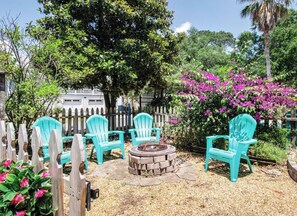 The picket fence gate opens up to our fire pit & seating area under the magnolia tree!