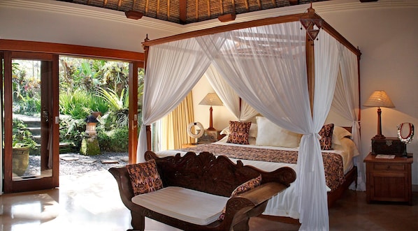 Elegant master bedroom with canopy bed, garden view, and cozy seating area