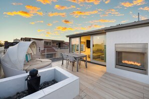 Cozy up by the outdoor fireplace on this inviting balcony, featuring comfy seating and a dining area perfect for al fresco meals or evening chats.