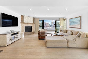Spacious and cozy living room featuring a large comfy couch, fireplace, smart TV, and easy access to the patio for indoor-outdoor relaxation.
